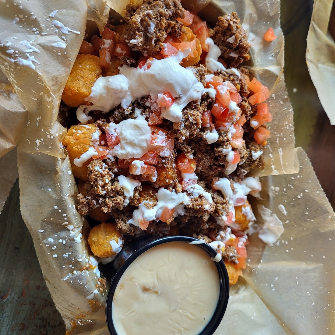 Nacho Average Fries: tots with chorizo and beef, tomato, sour cream, and beer cheese